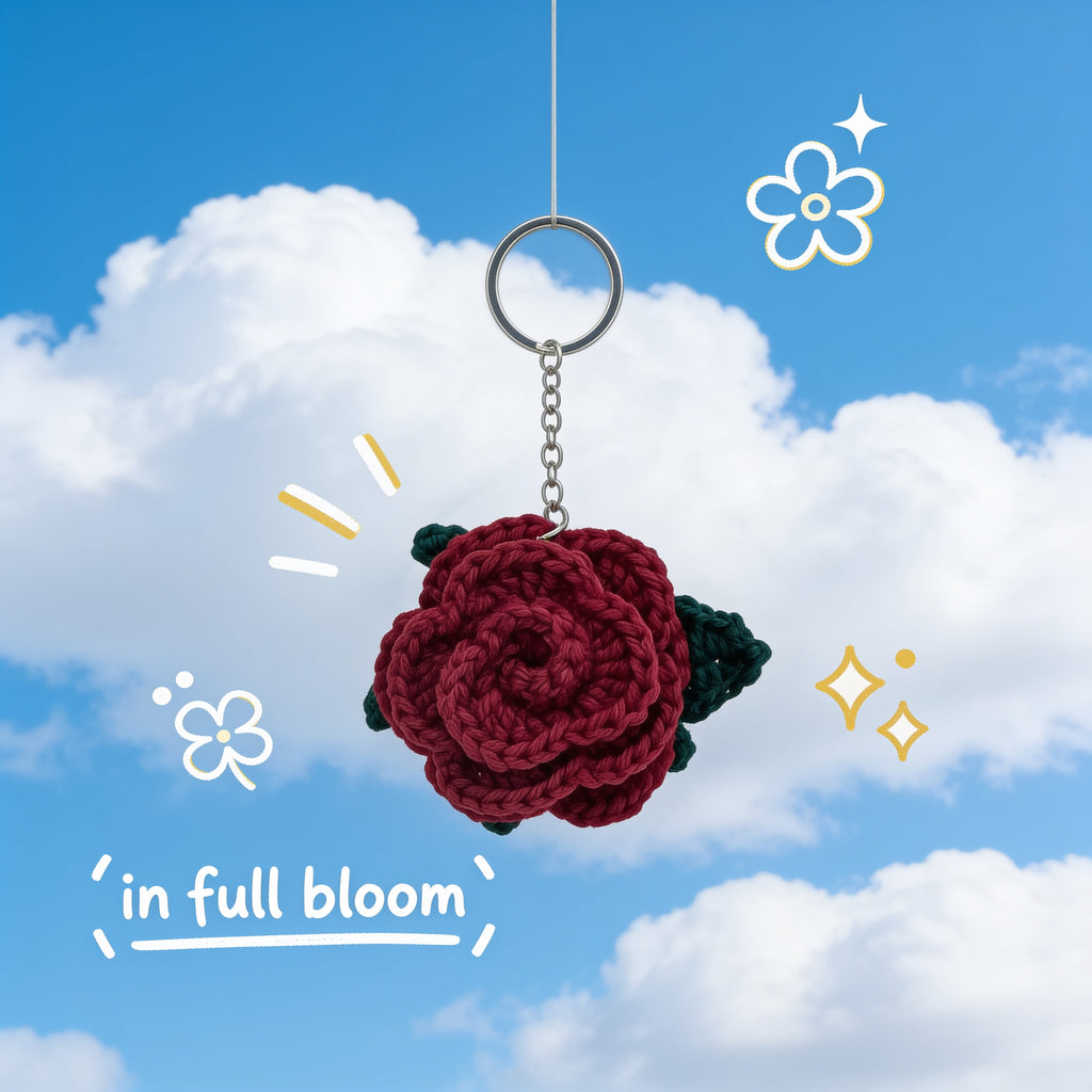 Handmade burgundy crochet rose keychain with small green leaves on a silver chain